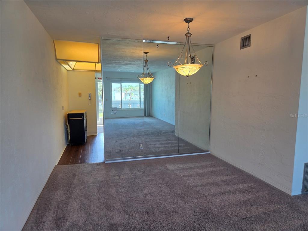 A dining area features a mirrored wall, a hanging light fixture, and carpeted flooring — 2454 AUSTRALIA WAY E UNIT 66, CLEARWATER, FL