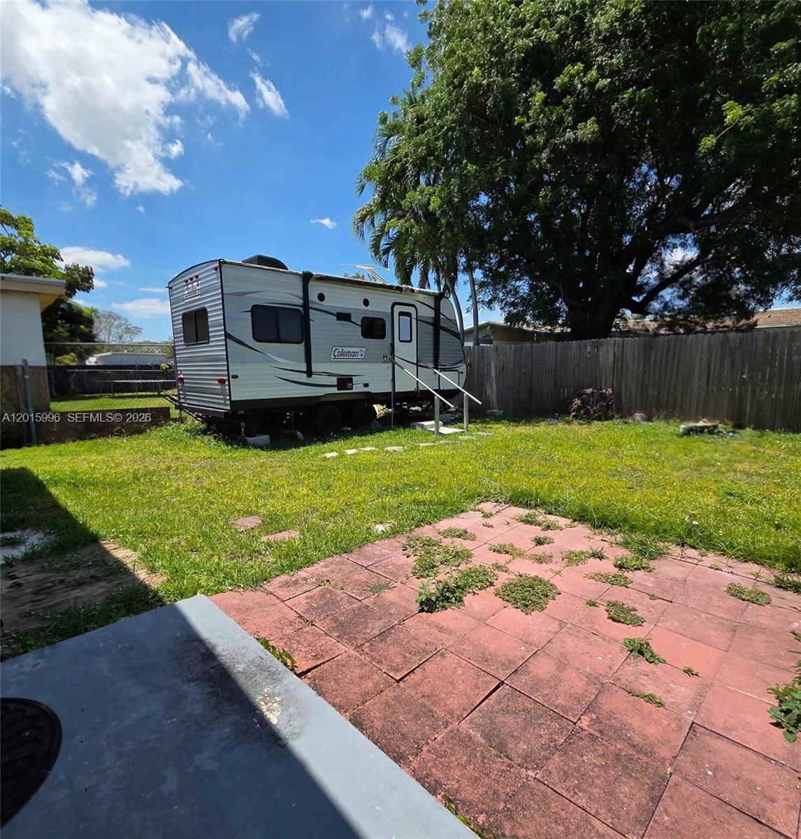 A Coleman travel trailer sits in a grassy backyard with a red brick patio — 11941 SW 200th St, Miami FL 33177, MIAMI, FL