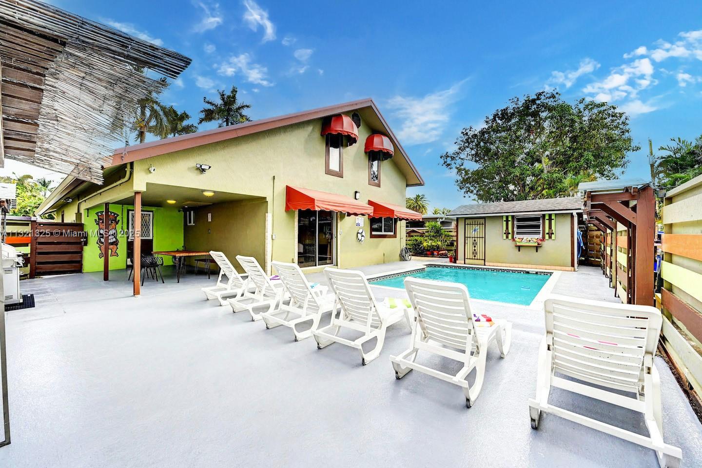 A backyard features a swimming pool, several lounge chairs, and a light green house — 1020 N 13th Ter, Hollywood FL 33019, HOLLYWOOD, FL