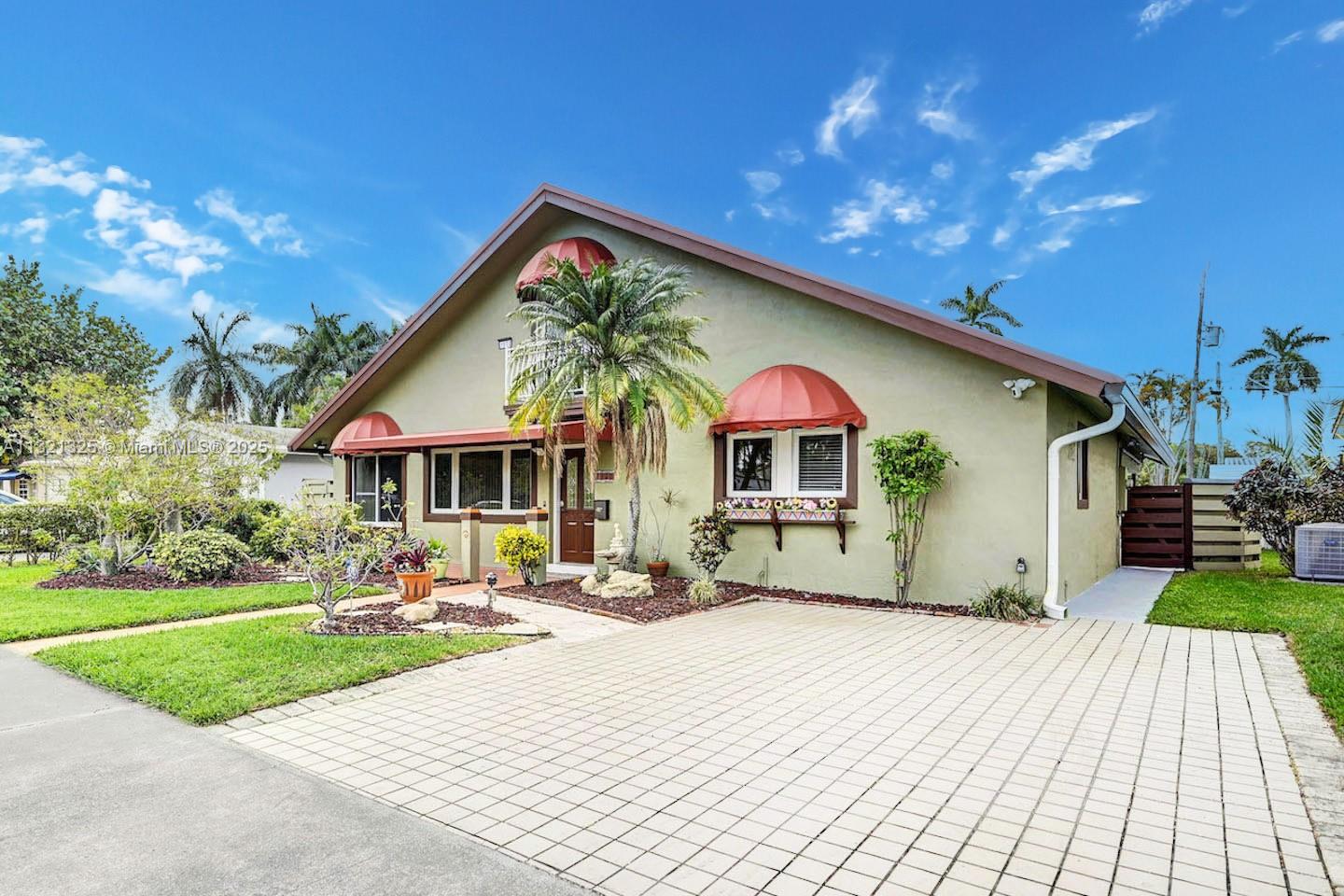 A single-story house with a paved driveway, red awnings, and a palm tree in front — 1020 N 13th Ter, Hollywood FL 33019, HOLLYWOOD, FL