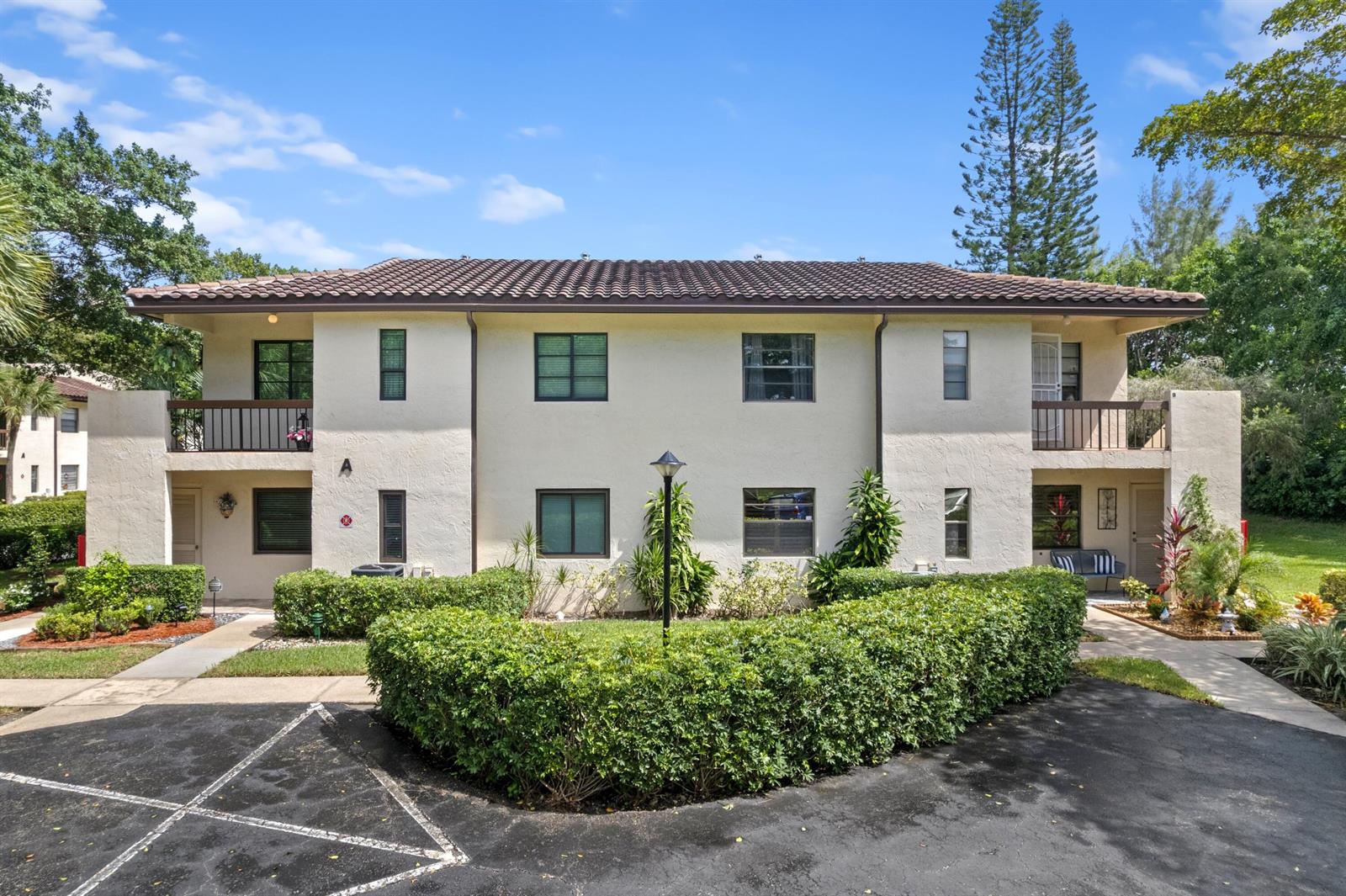 A two-story apartment building with a tiled roof, balconies, and a landscaped front yard — 21734 Arriba Real # 32b, Boca Raton FL 33433, BOCA RATON, FL