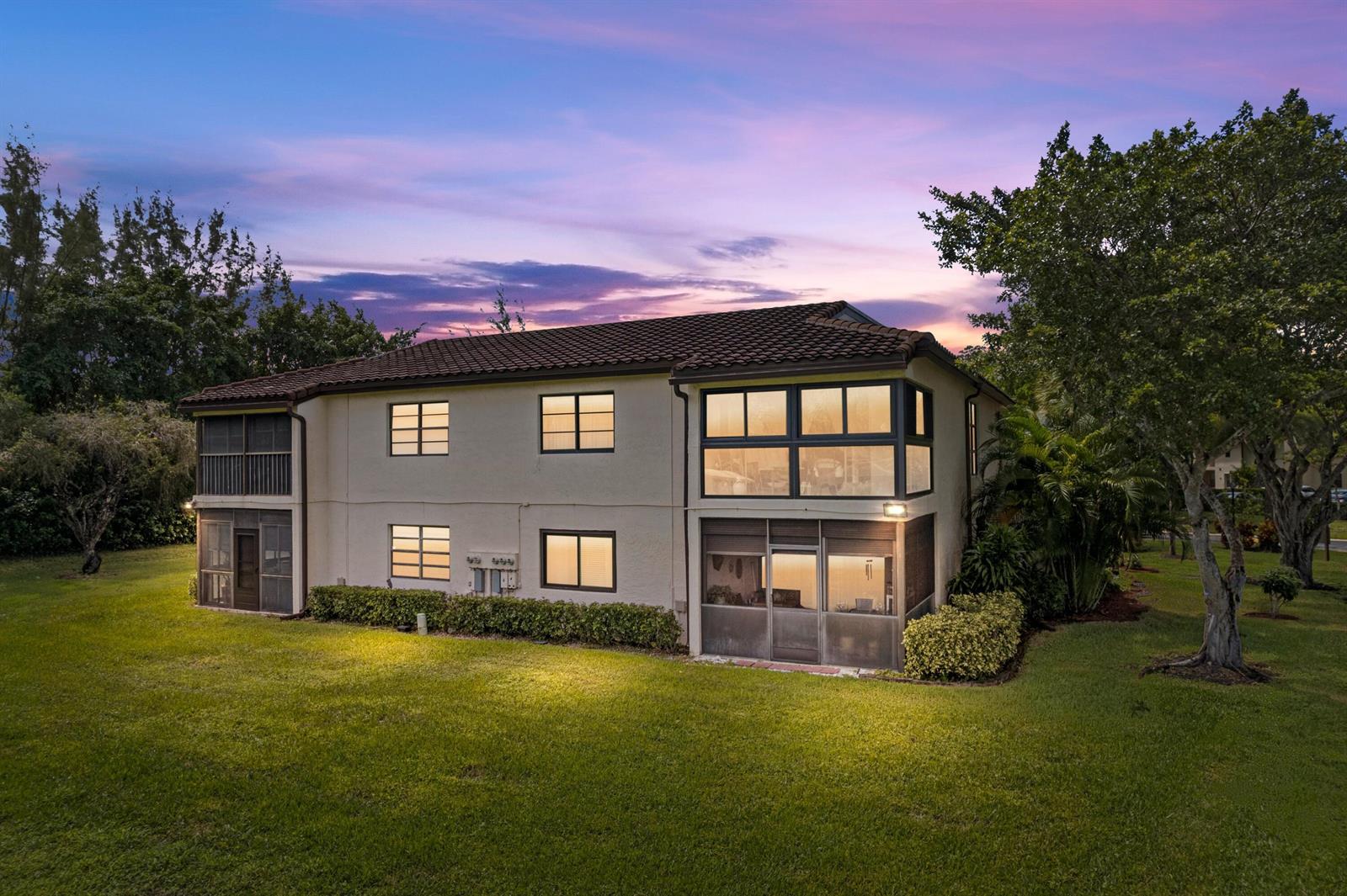 An exterior view of a two-story residential building with a screened patio and balcony — 21734 Arriba Real # 32b, Boca Raton FL 33433, BOCA RATON, FL