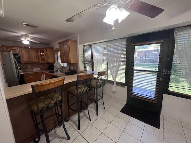 A kitchen features wooden cabinets, a breakfast bar with stools, and a glass-paned door — 101 GRAND PLAZA DRIVE UNIT I20, ORANGE CITY, FL