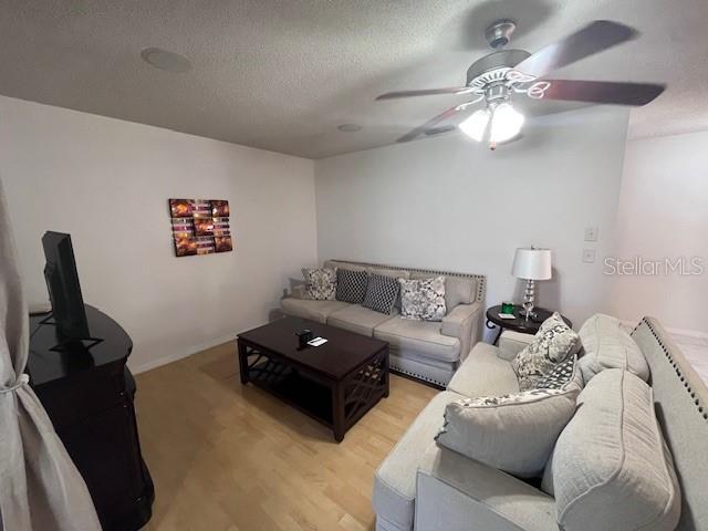 A living room features a light-colored sofa, a dark wood coffee table, and a ceiling fan — 101 GRAND PLAZA DRIVE UNIT I20, ORANGE CITY, FL