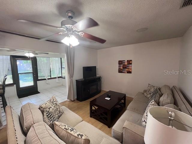 A living room features a ceiling fan, a television on a stand, and a beige sofa — 101 GRAND PLAZA DRIVE UNIT I20, ORANGE CITY, FL