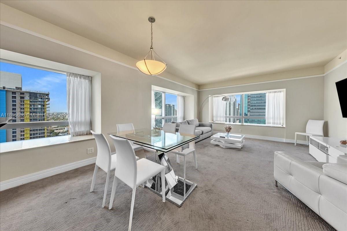 A living and dining area with a glass table, white chairs, and city views — 1435 Brickell Ave # 3112, Miami FL 33131, MIAMI, FL