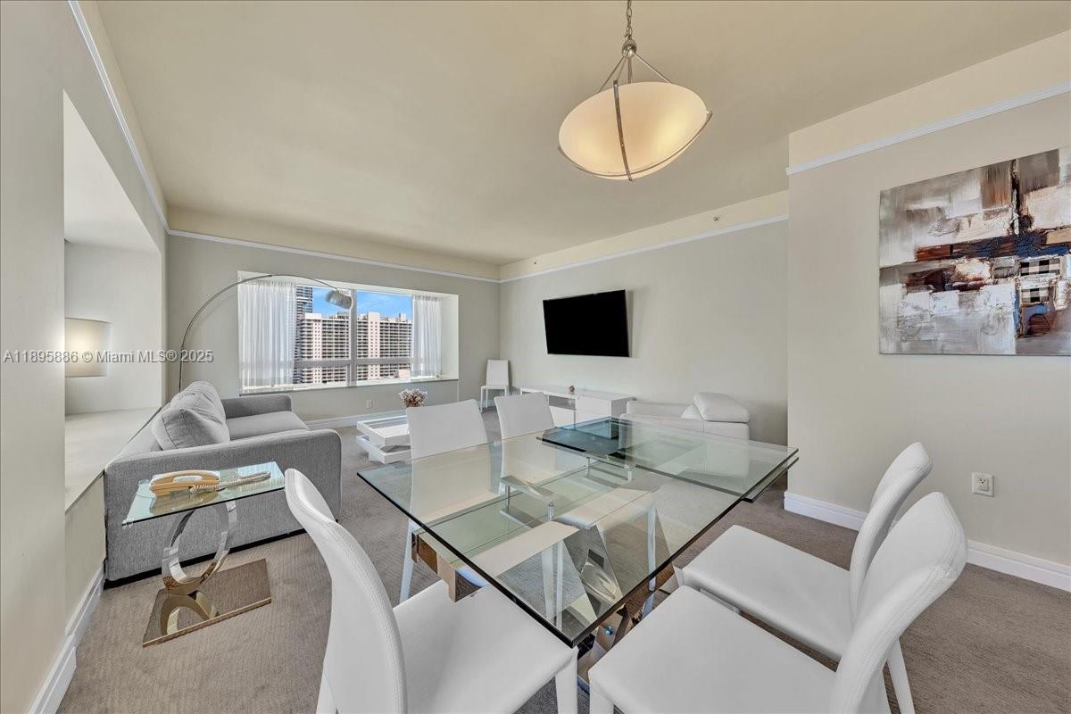 A bright living and dining area features a glass table, white chairs, and large windows — 1435 Brickell Ave # 3112, Miami FL 33131, MIAMI, FL