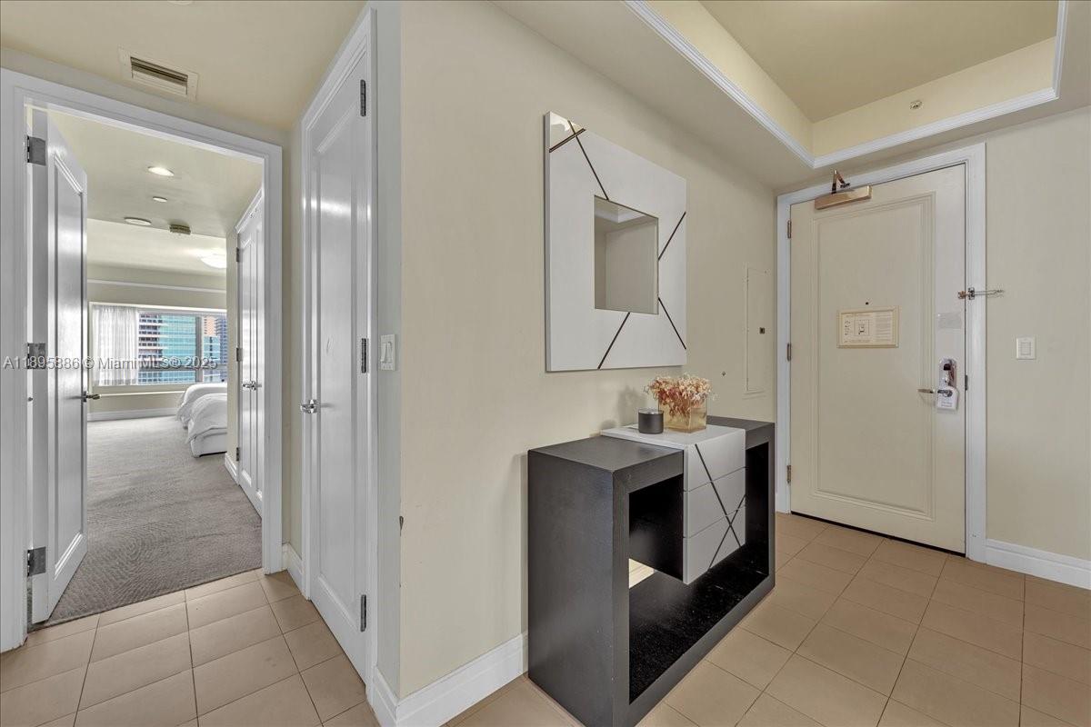 An entryway features a console table, wall art, and a doorway leading to a bedroom — 1435 Brickell Ave # 3112, Miami FL 33131, MIAMI, FL