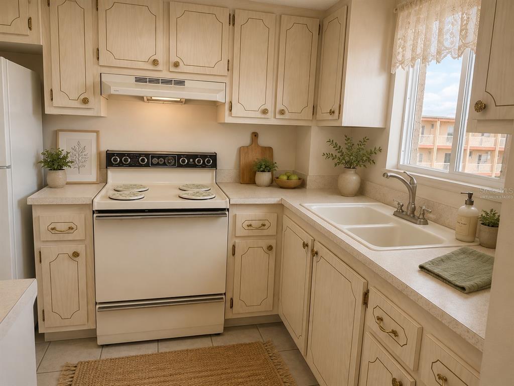 A kitchen with light wood cabinets, white appliances, a double sink, and a window — 3973 LAKE BAYSHORE DRIVE UNIT 503, BRADENTON, FL