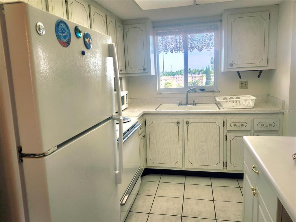A kitchen features white cabinets, a white refrigerator, a window above the sink, and tile — 3973 LAKE BAYSHORE DRIVE UNIT 503, BRADENTON, FL