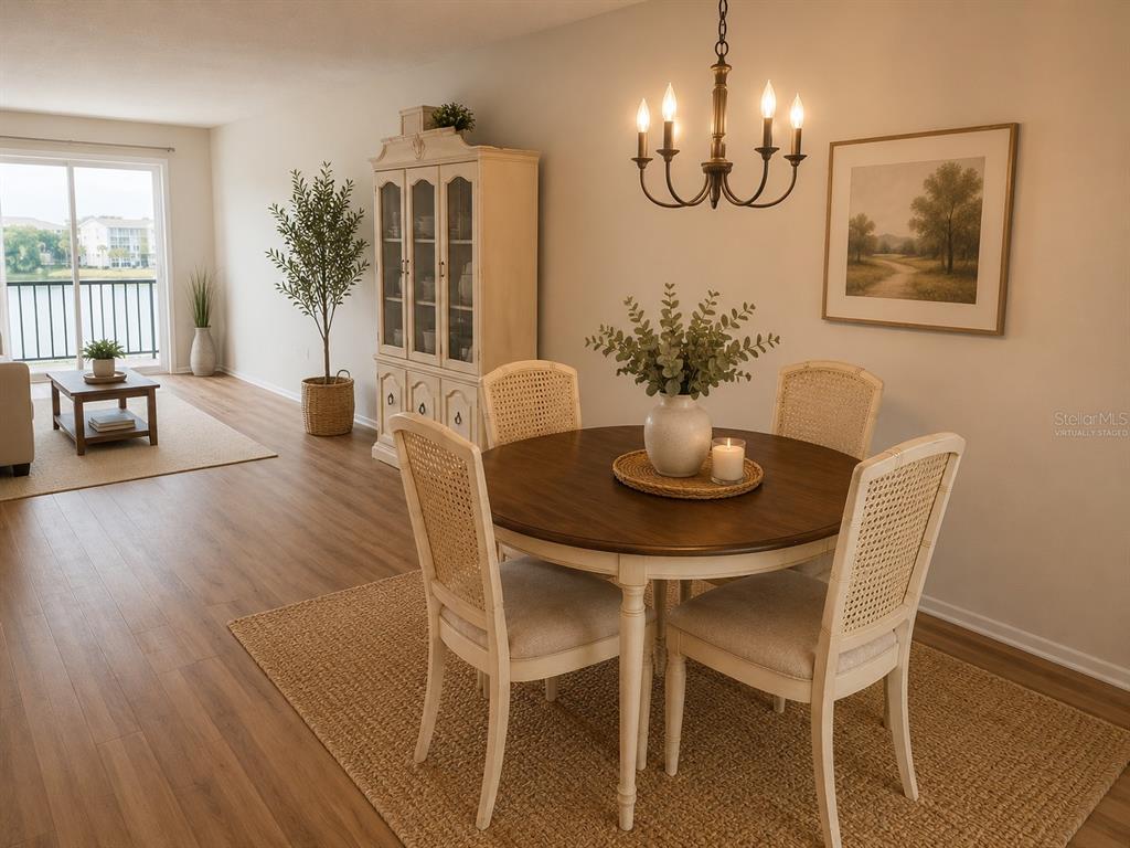 A dining area with a round wooden table, cane-back chairs, and a hutch on wood flooring — 3973 LAKE BAYSHORE DRIVE UNIT 503, BRADENTON, FL