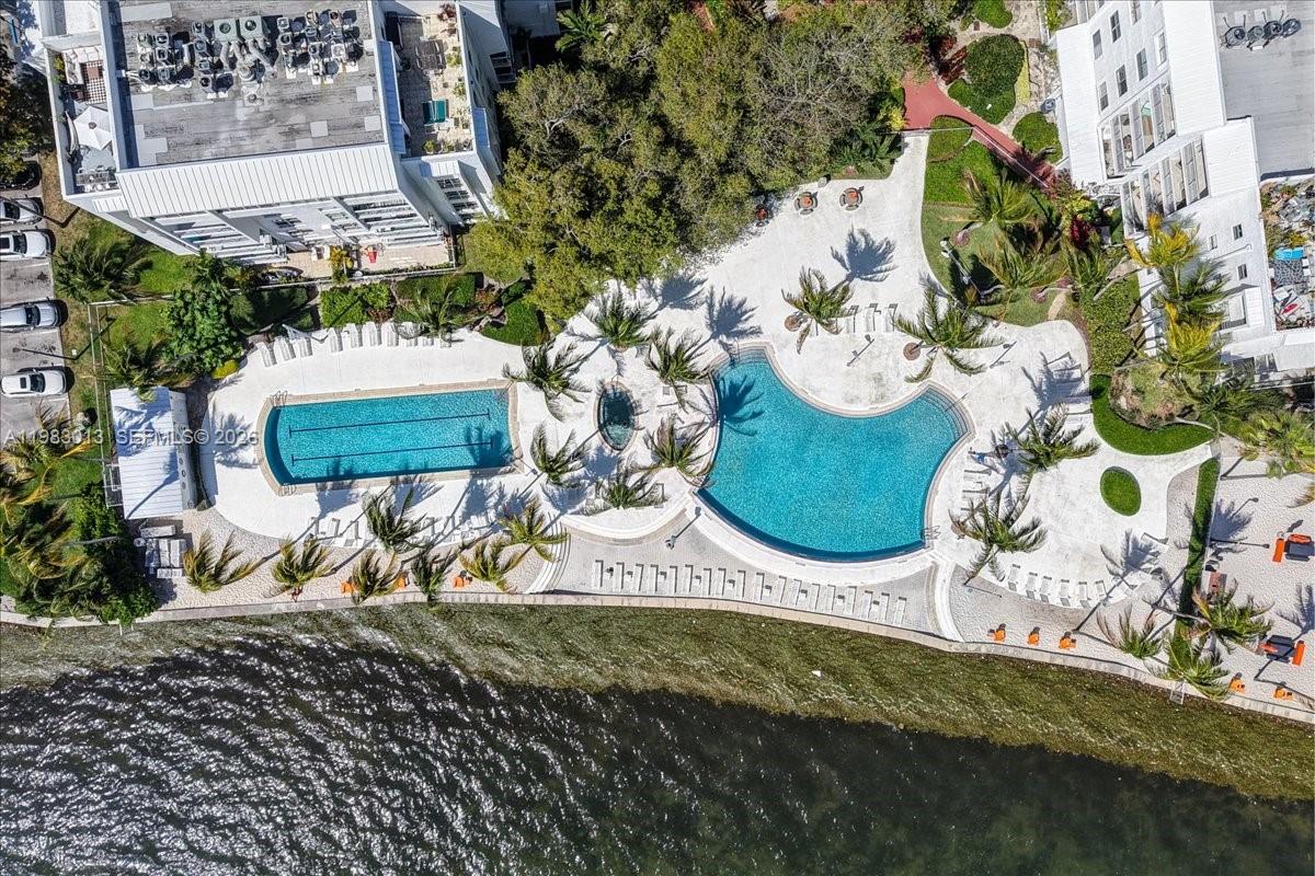 An aerial view shows two swimming pools, a hot tub, and lounge chairs by water — 777 NE 62nd St # C211, Miami FL 33138, MIAMI, FL