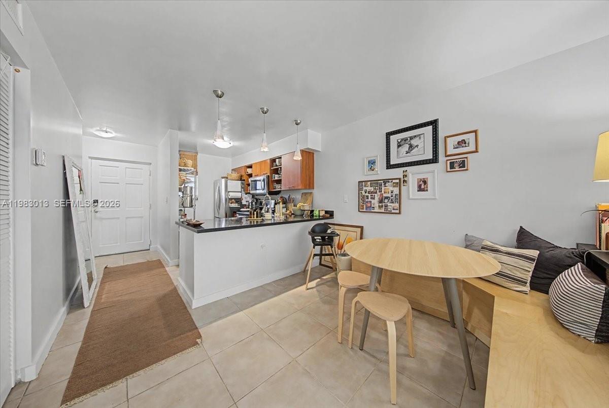 A kitchen with a breakfast bar opens into a dining area with a corner bench — 777 NE 62nd St # C211, Miami FL 33138, MIAMI, FL