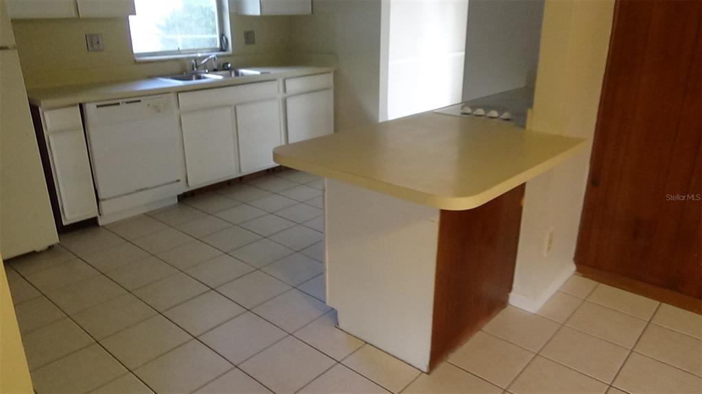 A kitchen features white cabinets, a peninsula with a light countertop, and tiled flooring — 2730 PRINCE JOHN ROAD, WINTER PARK, FL