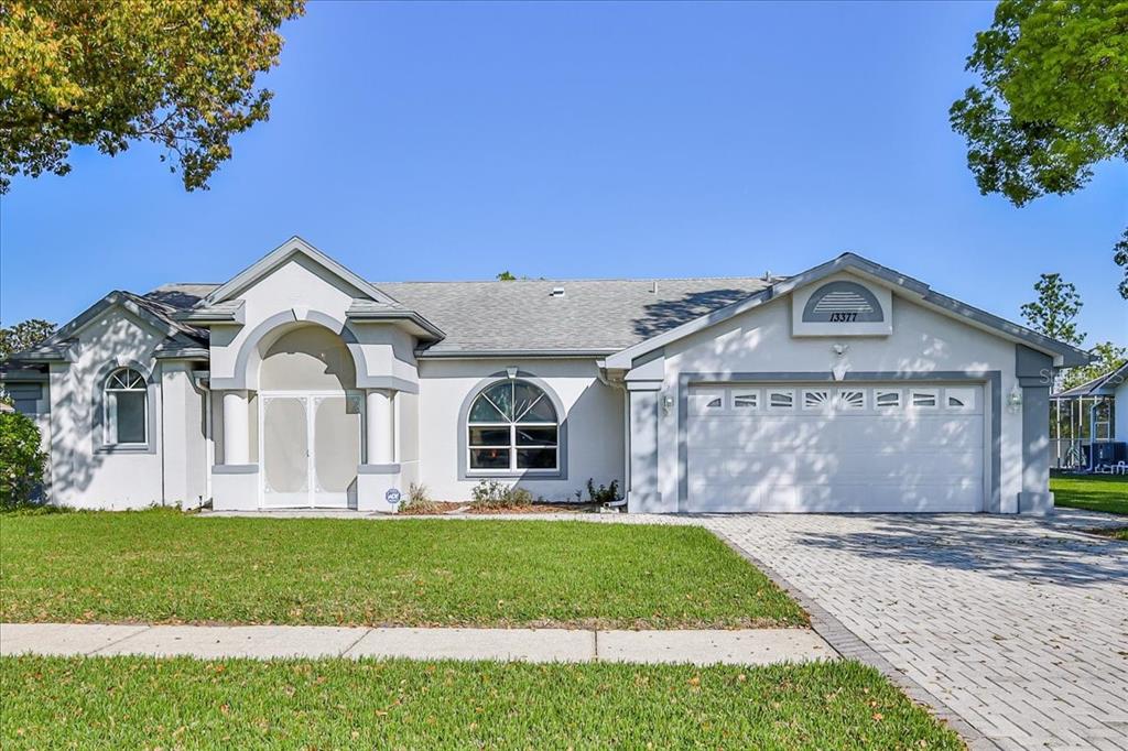A single-story house with a beige stucco exterior, arched windows, and a two-car garage — 13377 BOLTON COURT, SPRING HILL, FL