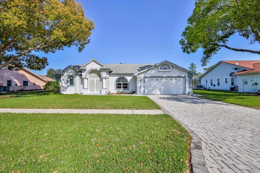 A single-story house with a white exterior, arched windows, and a paved driveway — 13377 BOLTON COURT, SPRING HILL, FL