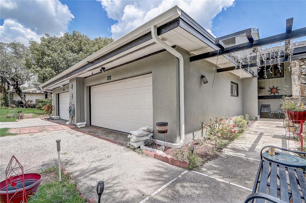 A view of a house exterior featuring two garage doors, a concrete driveway, and landscaping — 32 NOTTINGHAM WAY, HAINES CITY, FL