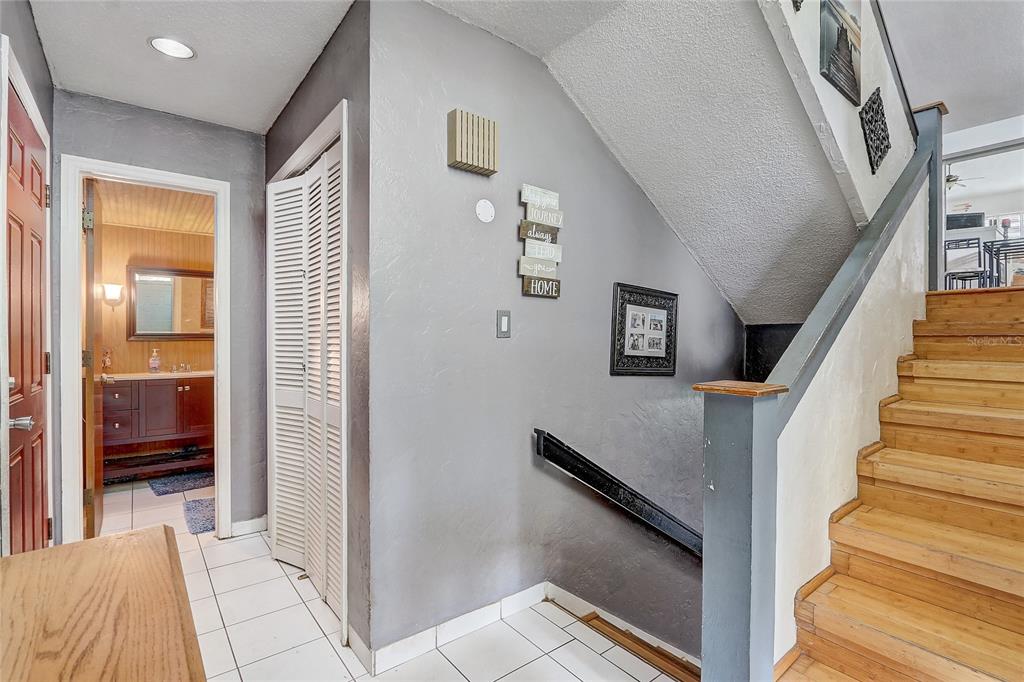 An entryway with white tile floors, a staircase with wooden steps, and a nearby bathroom — 32 NOTTINGHAM WAY, HAINES CITY, FL