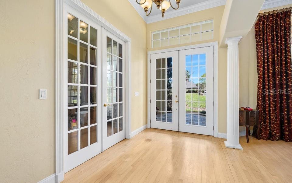 A room with light wood floors, French doors, a white column, and a chandelier — 6 BROADWATER DRIVE, ORMOND BEACH, FL