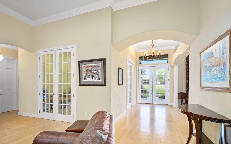 An entryway with light wood floors, arched openings, French doors, and a chandelier — 6 BROADWATER DRIVE, ORMOND BEACH, FL