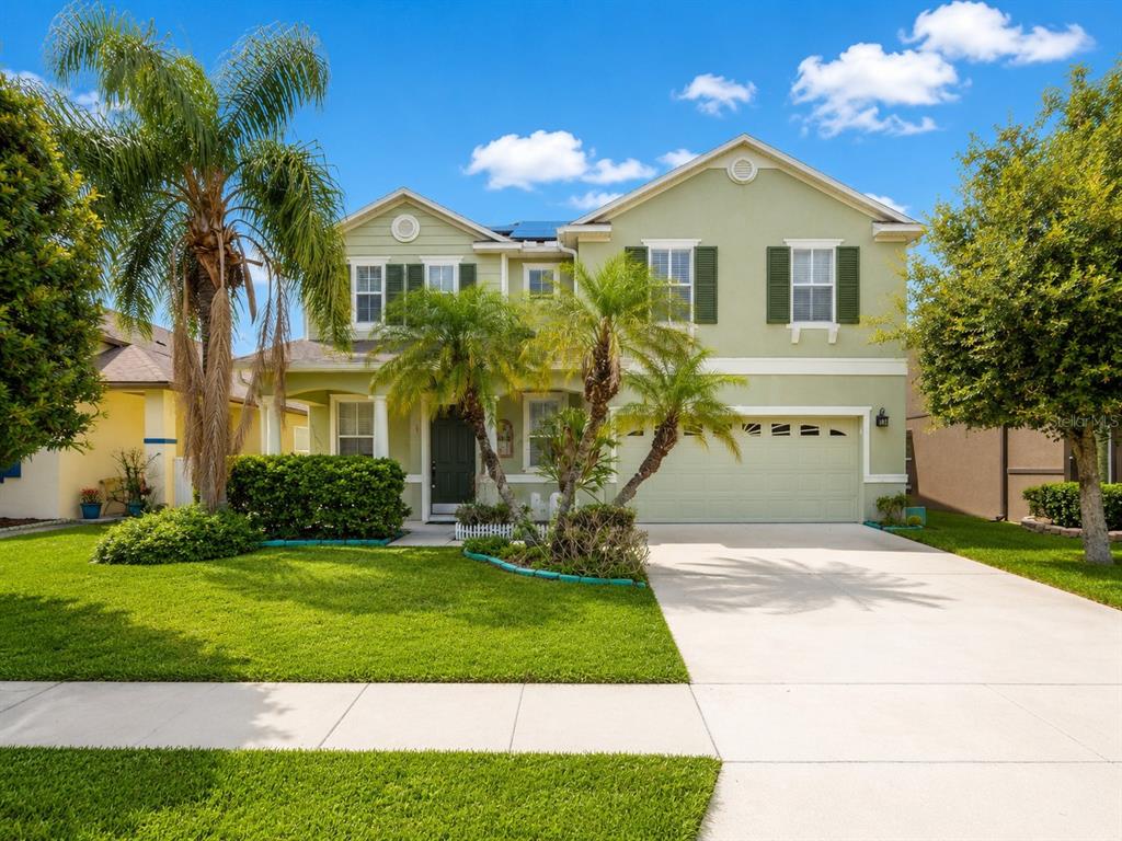 A two-story, light green suburban house with a two-car garage and a palm-lined front yard — 2808 PAYNES PRAIRIE CIRCLE, KISSIMMEE, FL