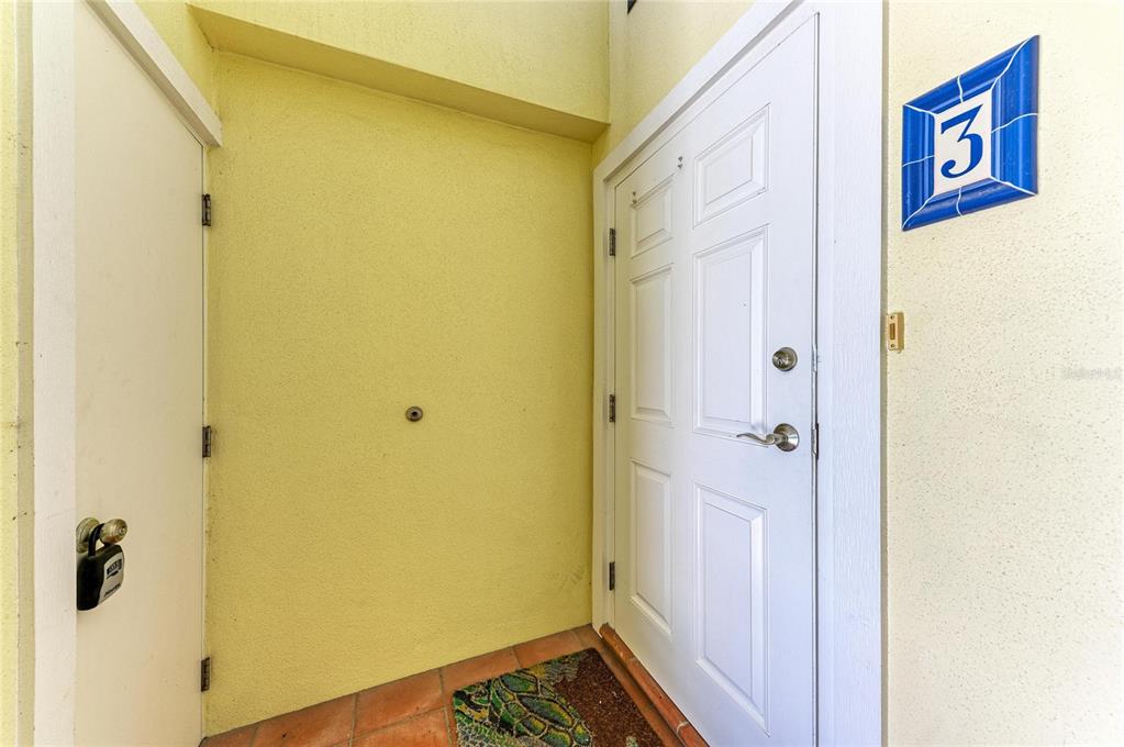 A white front door with a number three sign sits next to a storage closet — 101 PALM AVENUE UNIT 3, ANNA MARIA, FL