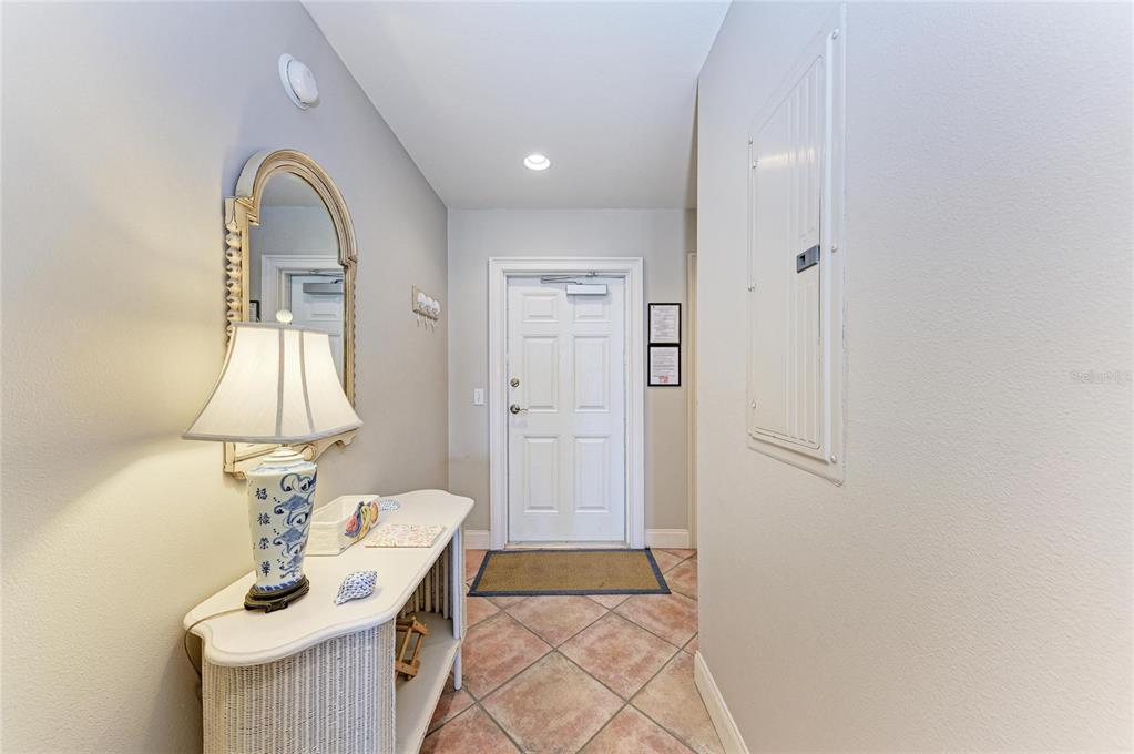 An entryway features a console table with a lamp, a wall mirror, and tiled flooring — 101 PALM AVENUE UNIT 3, ANNA MARIA, FL