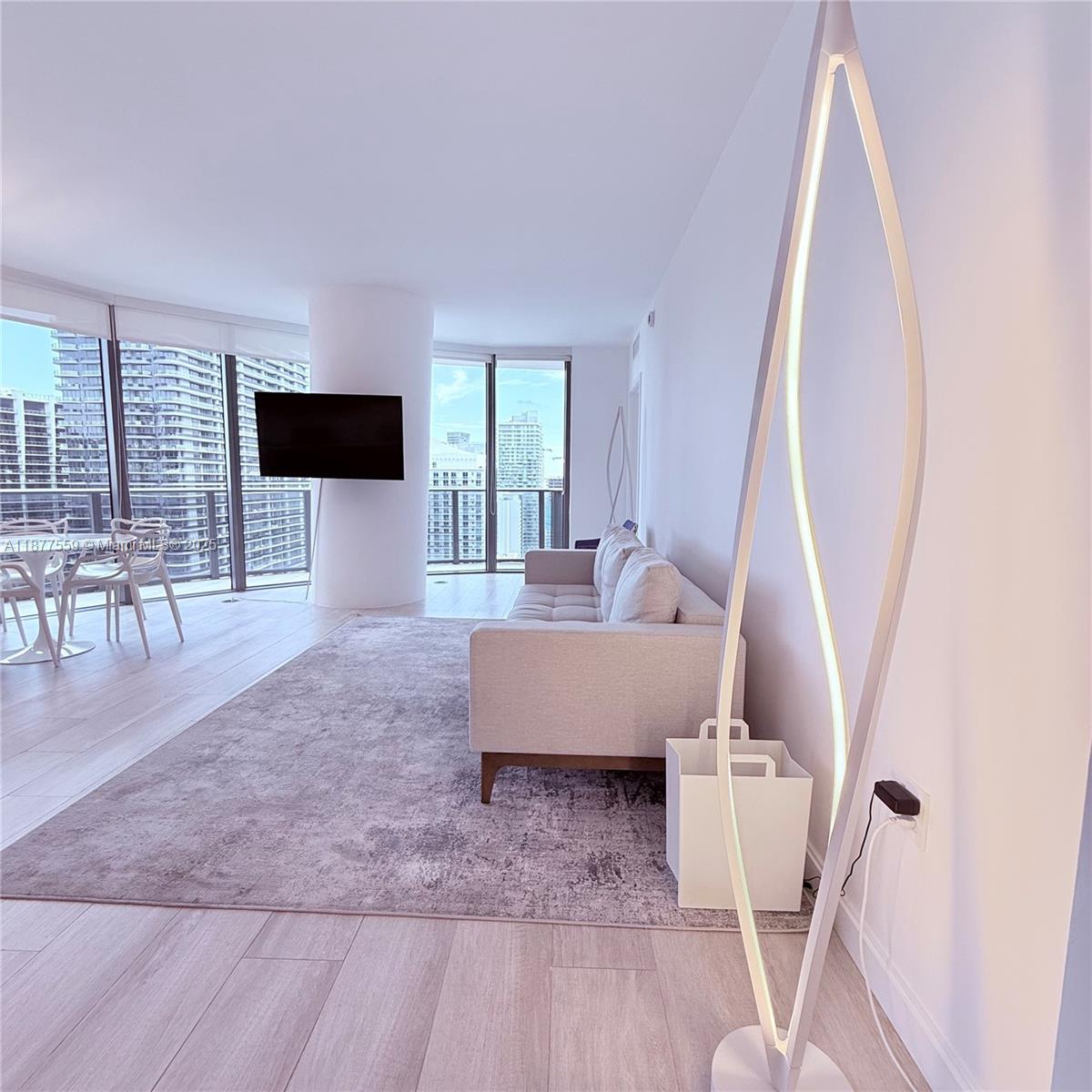 A modern living room features a light-colored sofa, a grey rug, and floor-to-ceiling windows — 55 SW 9th St # 4003, Miami FL 33130, MIAMI, FL