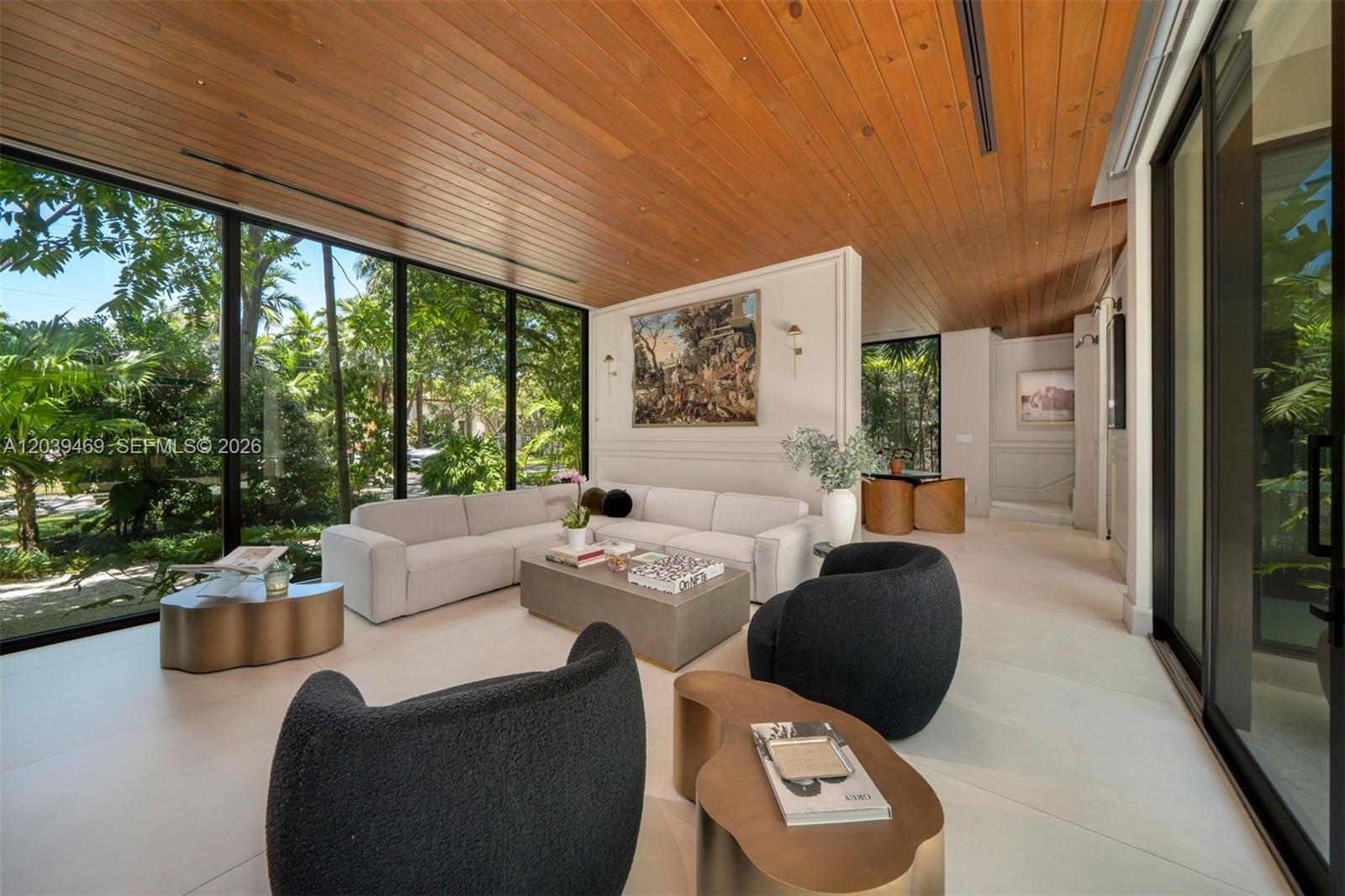 A modern living room features floor-to-ceiling windows, a wood-paneled ceiling, and a neutral sofa — 7851 SW 48th Pl, Miami FL 33143, MIAMI, FL