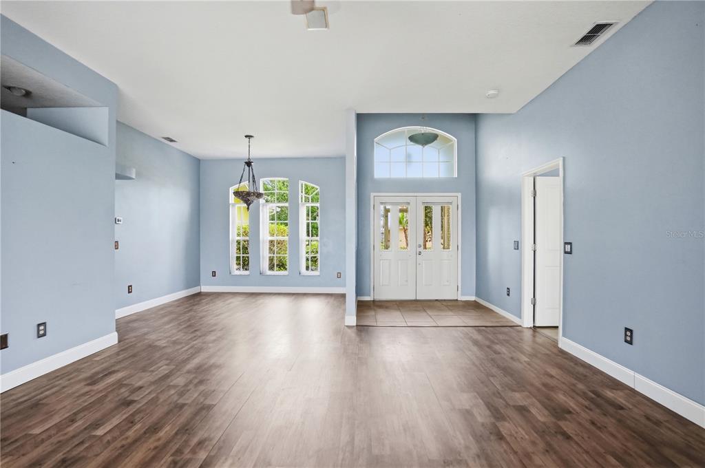 An empty room with light blue walls, wood-look flooring, a chandelier, and a double-door entrance — 18131 RIVARD BOULEVARD, BROOKSVILLE, FL