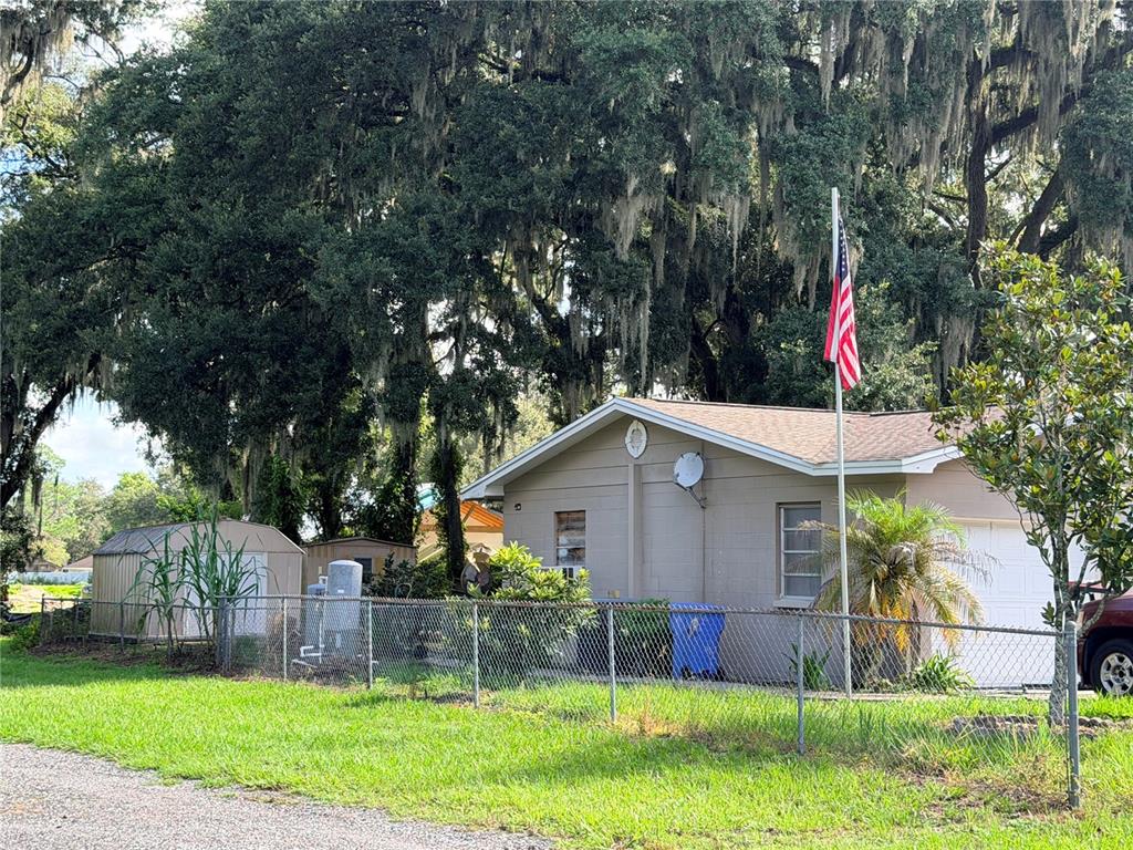 A single-story house with a chain-link fence, a flagpole, and large oak trees — 2028 PLEASANT ACRE DRIVE, PLANT CITY, FL