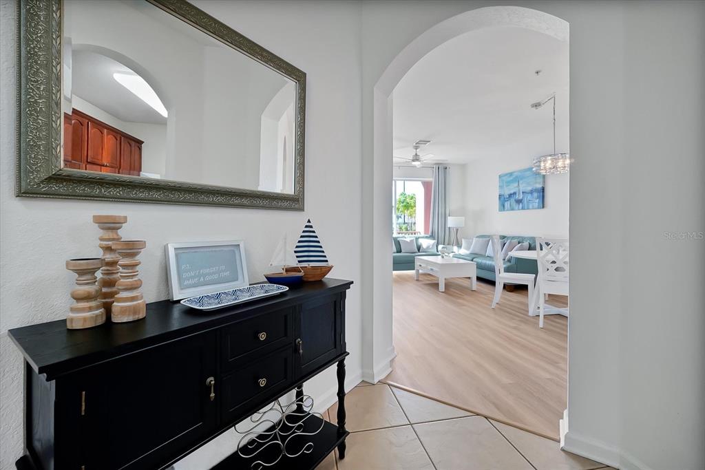 A black console table sits in a tiled entryway leading into a bright living area — 4862 CAYVIEW AVENUE UNIT 102, ORLANDO, FL
