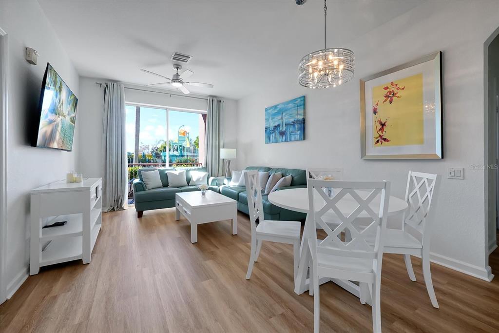 A living and dining area features a teal sofa, white furniture, and a ceiling fan — 4862 CAYVIEW AVENUE UNIT 102, ORLANDO, FL