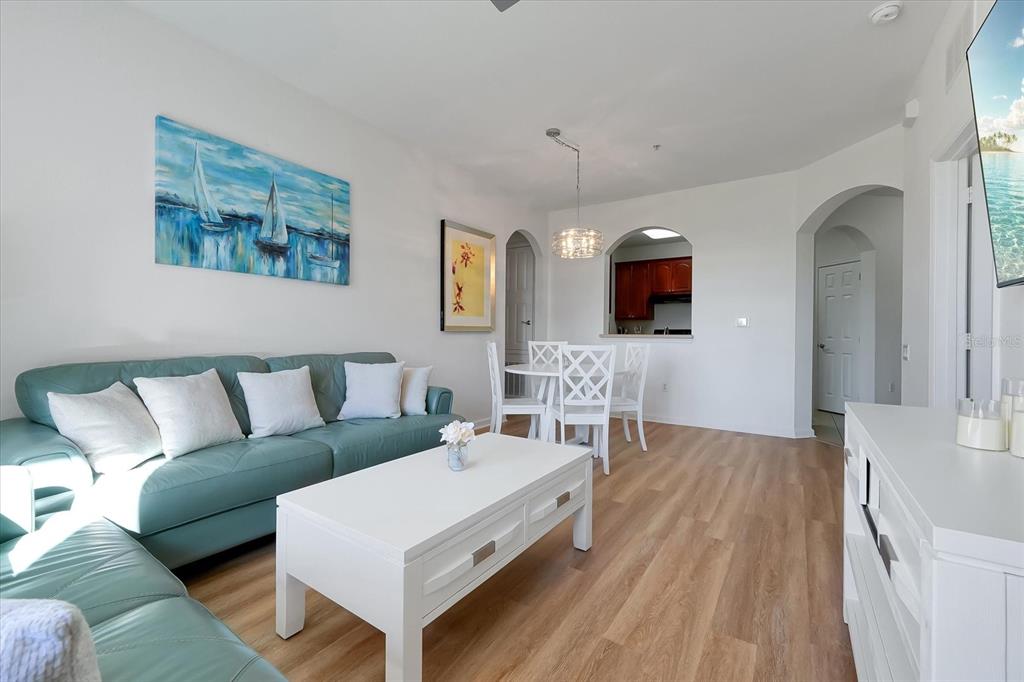 A living room with a teal sofa, white coffee table, and a dining area — 4862 CAYVIEW AVENUE UNIT 102, ORLANDO, FL