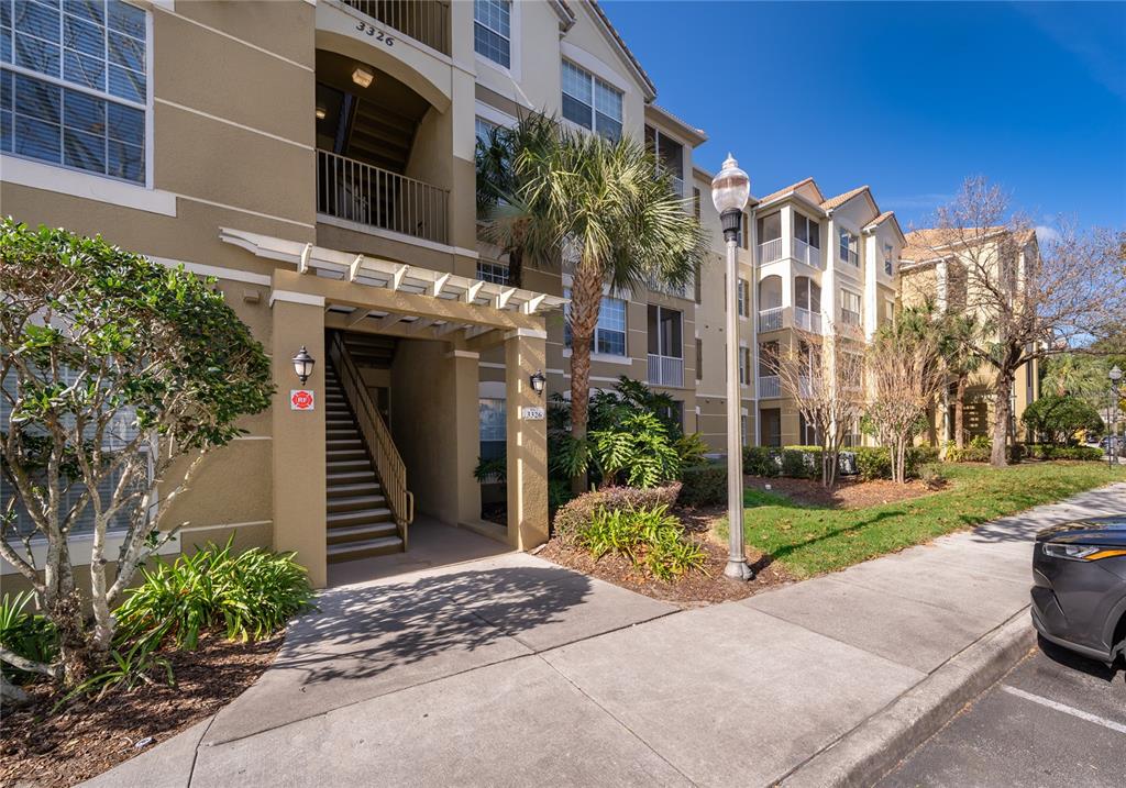 An exterior view of a multi-story apartment building with a covered staircase entrance — 3326 ROBERT TRENT JONES DRIVE UNIT 107, ORLANDO, FL