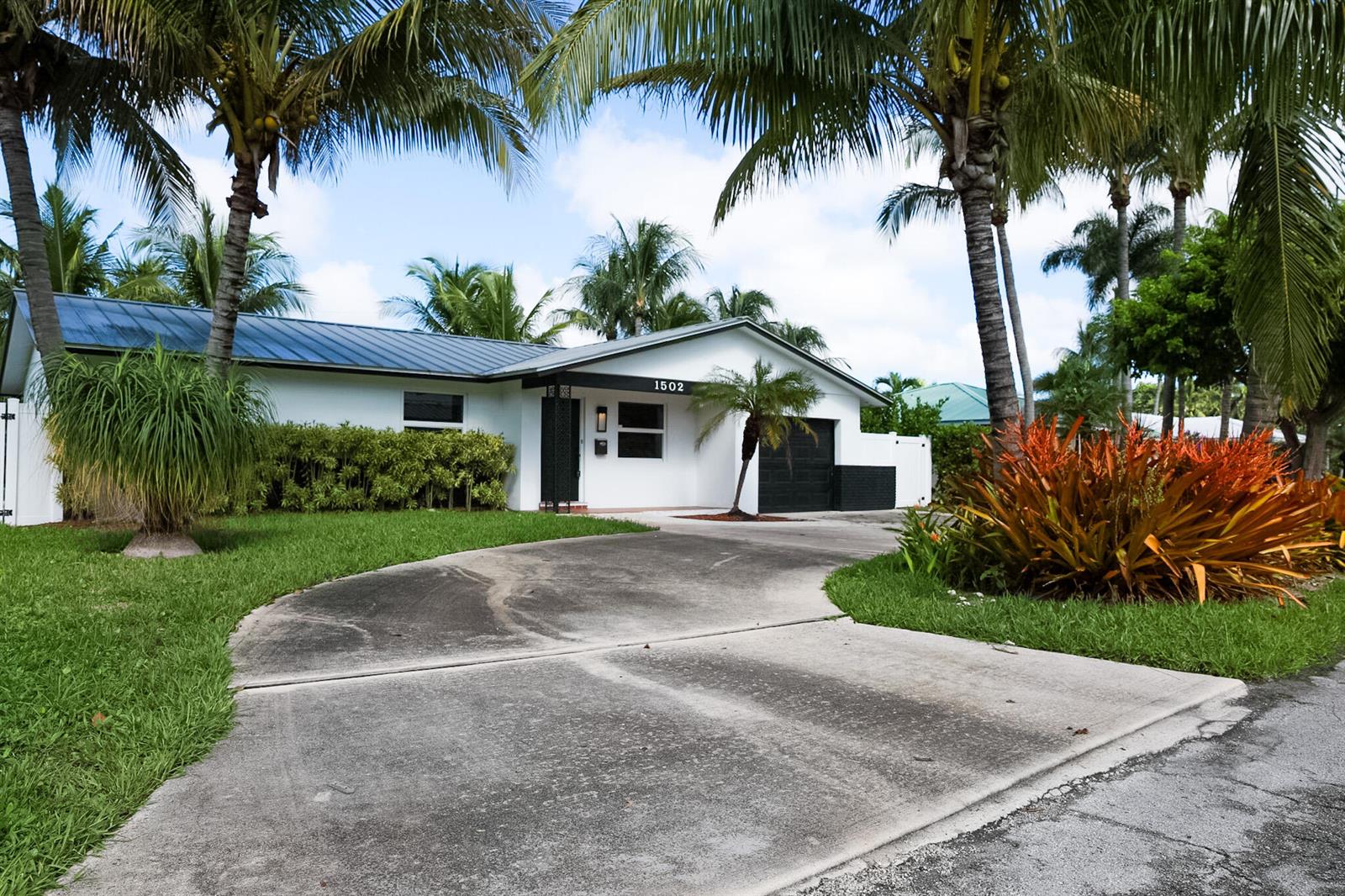A white single-story house with a metal roof, black accents, and a concrete driveway — 1502 NW 4th Avenue, Delray Beach FL 33432, DELRAY BEACH, FL