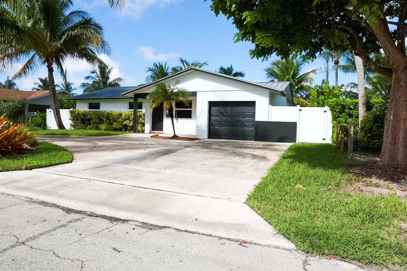 A white single-story house with a black garage door and a concrete driveway — 1502 NW 4th Avenue, Delray Beach FL 33432, DELRAY BEACH, FL