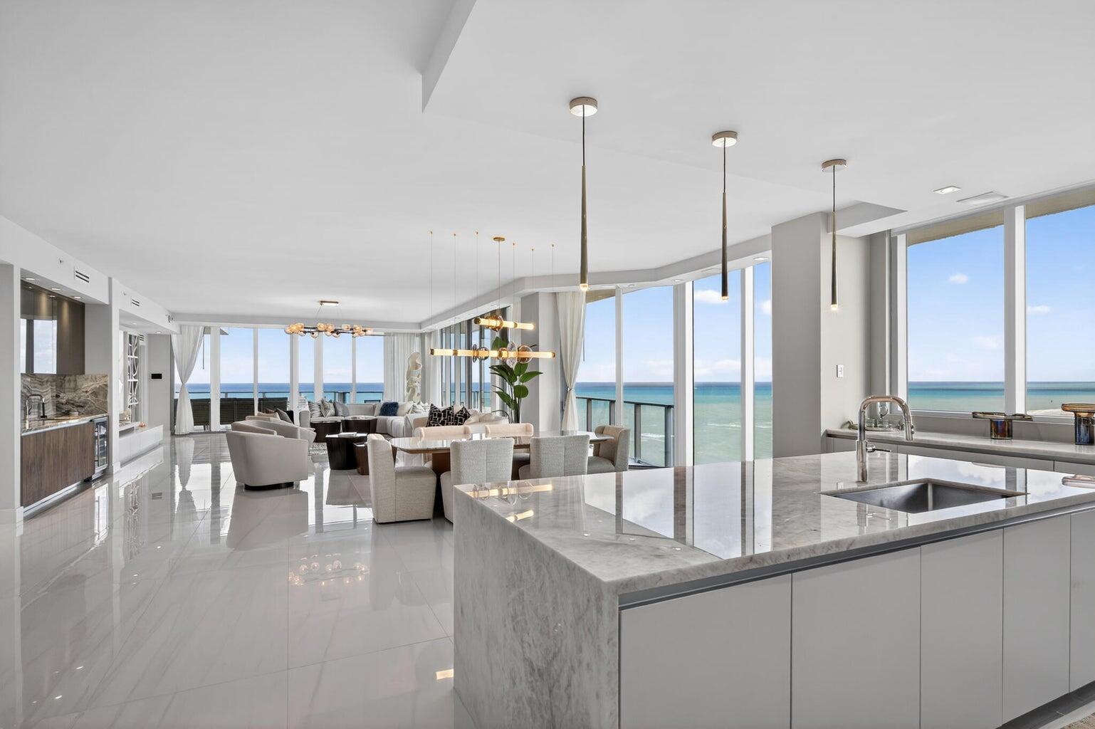 A modern open-concept kitchen and living area with marble countertops, tile floors, and ocean views — 3100 N Ocean Drive, Riviera Beach FL 33404, RIVIERA BEACH, FL