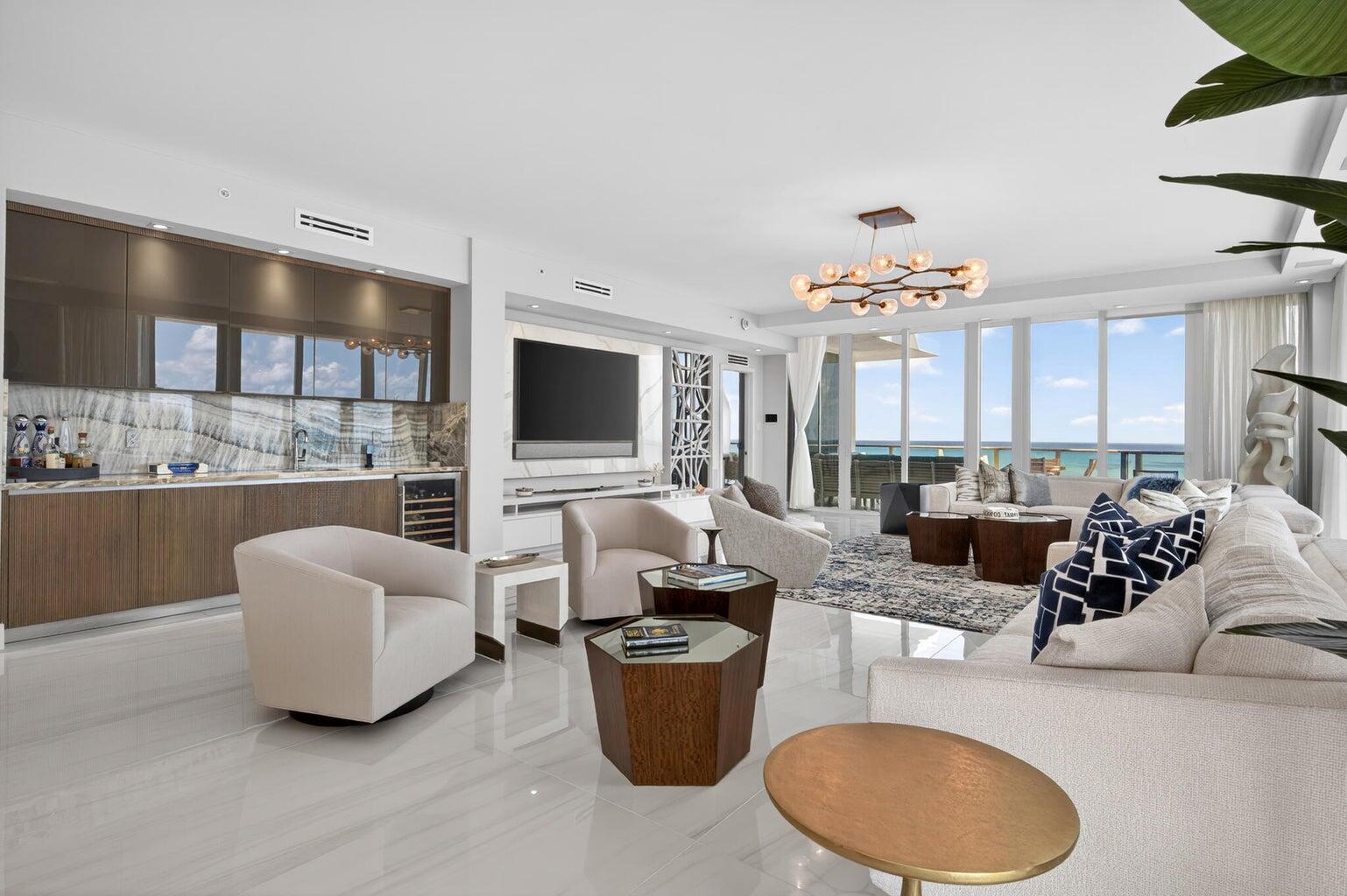 A modern living room features a wet bar, neutral furniture, and floor-to-ceiling windows overlooking the ocean — 3100 N Ocean Drive, Riviera Beach FL 33404, RIVIERA BEACH, FL