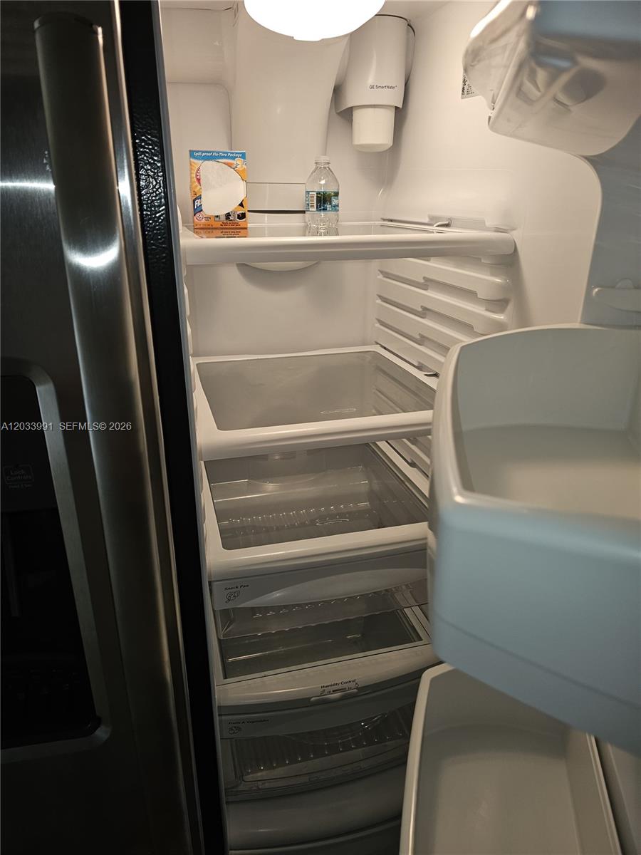 The interior of a clean, empty refrigerator features glass shelves and multiple storage drawers — 17066 SW 95th Ter, Miami FL 33196, MIAMI, FL