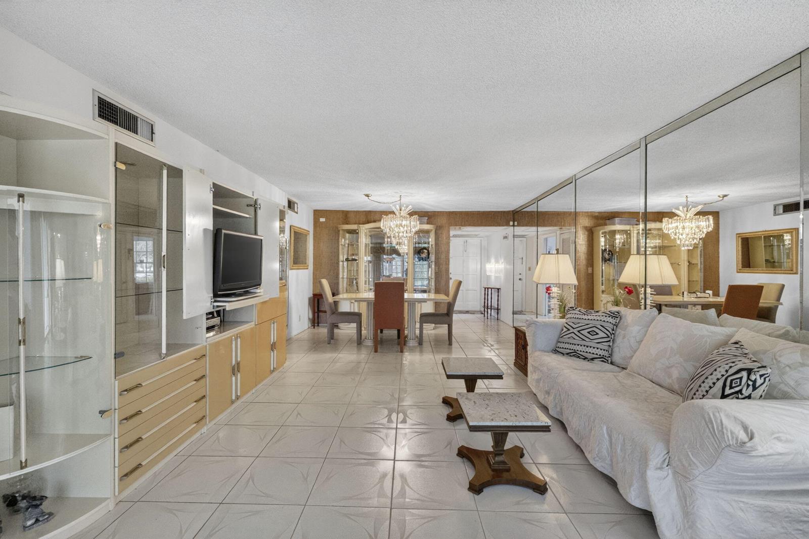 A living and dining area with tiled floors, mirrored walls, and built-in cabinetry — 3000 S Course Drive # 103, Pompano Beach FL 33069, POMPANO BEACH, FL