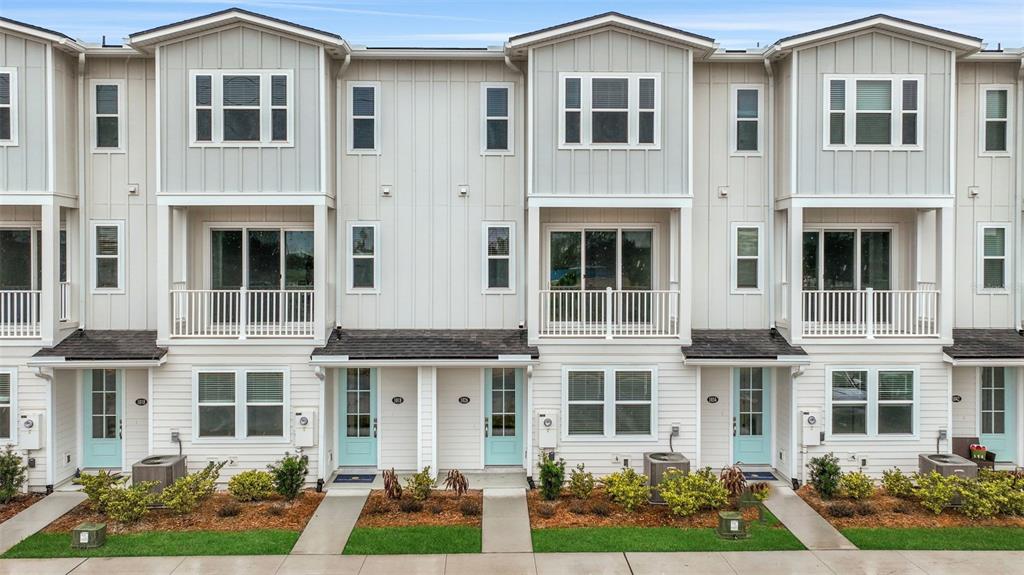 A row of modern three-story townhomes features light-colored siding, balconies, and light blue front doors — 6 N BEACH WAY, JACKSONVILLE BEACH, FL