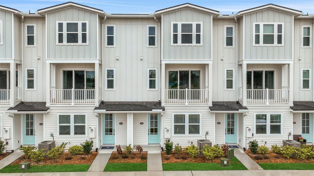A row of three-story townhomes features light-colored vertical siding, balconies, and light blue front doors — 6 N BEACH WAY, JACKSONVILLE BEACH, FL