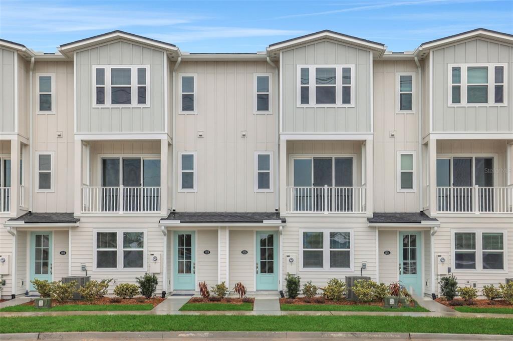 A row of three-story townhouses with light-colored siding, balconies, and light blue front doors — 6 N BEACH WAY, JACKSONVILLE BEACH, FL