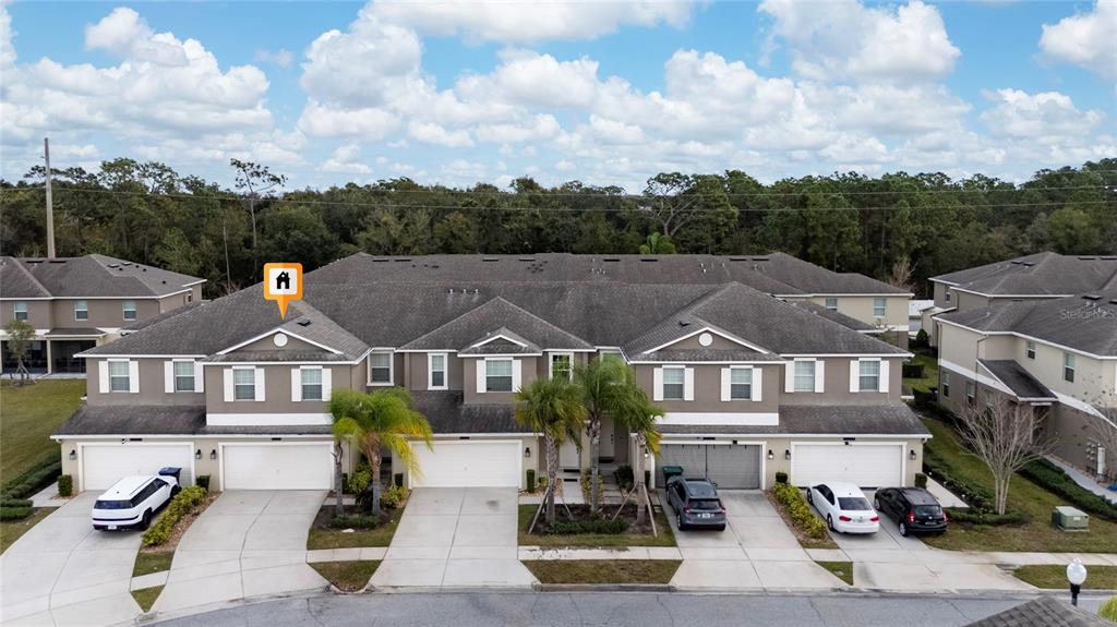 An aerial view of a multi-unit townhouse complex with attached garages and paved driveways — 15215 PACEY COVE DRIVE, ORLANDO, FL