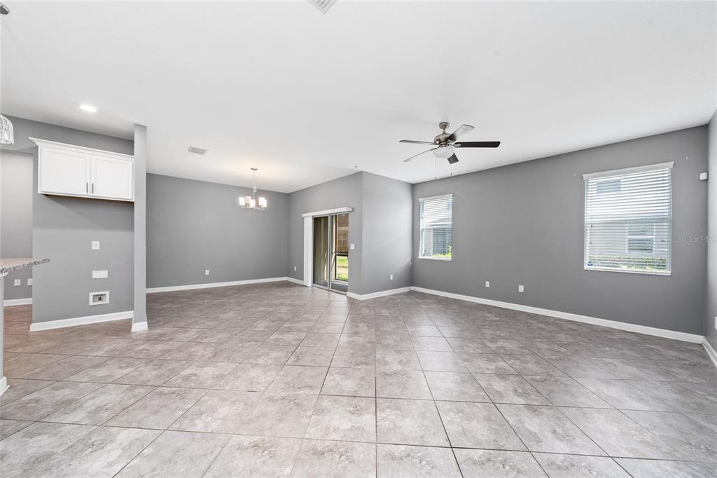 An open-concept living and dining area features gray walls, tile flooring, and a ceiling fan — 15215 PACEY COVE DRIVE, ORLANDO, FL