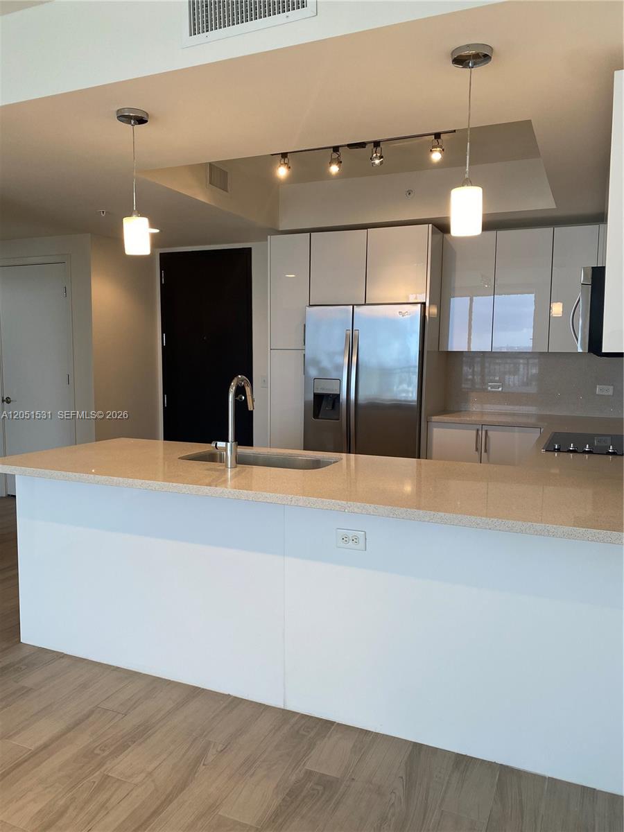 A kitchen features a white island with a sink, stainless steel appliances, and glossy cabinets — 999 SW 1 AVE # 3209, Miami FL 33130, MIAMI, FL