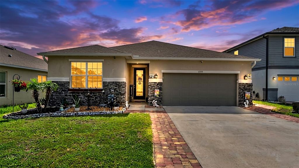 A single-story house with a stone facade, a two-car garage, and a brick paver driveway — 7589 MUSCOVY DRIVE, LAKELAND, FL