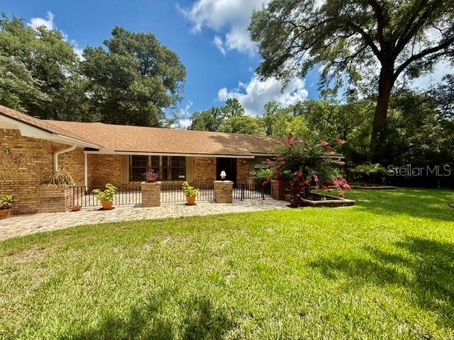 A brick house with a shingled roof features a front patio and large lawn — 543 PRINCEWOOD DRIVE, DELAND, FL
