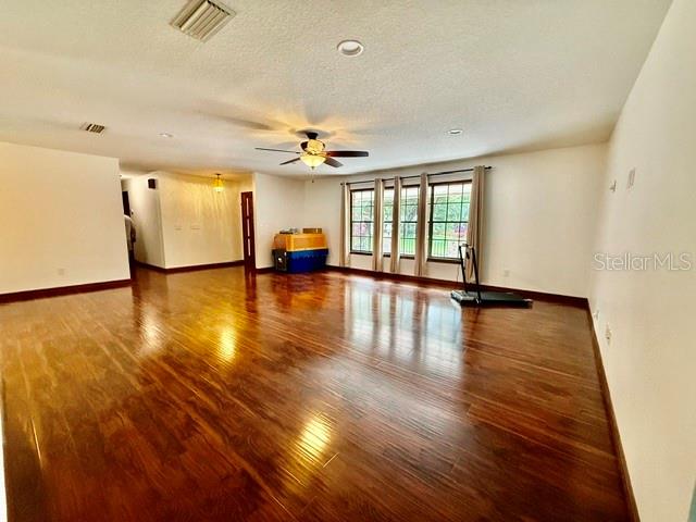 A spacious room features dark wood flooring, a ceiling fan, and large windows — 543 PRINCEWOOD DRIVE, DELAND, FL